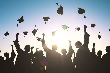 student thwowing mortarboards in air