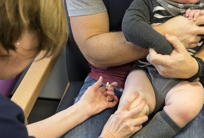 A nurse giving a baby an injection in its leg