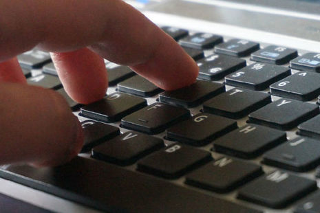 Stock image of a hand typing on a laptop.