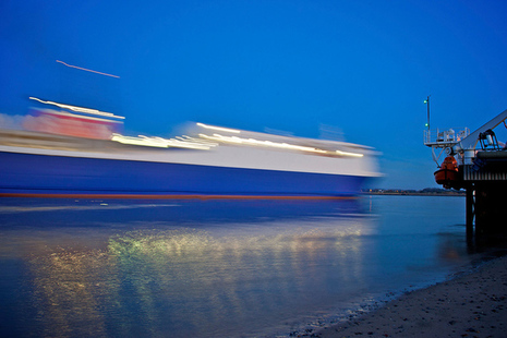 cargo ship at dusk, close to shore with lights visible
