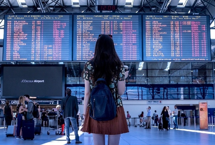 air passenger in front of overly detailed departure board