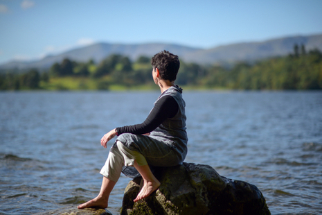 Local artist Caroline Stow sitting on a rock and looking over Windermere.