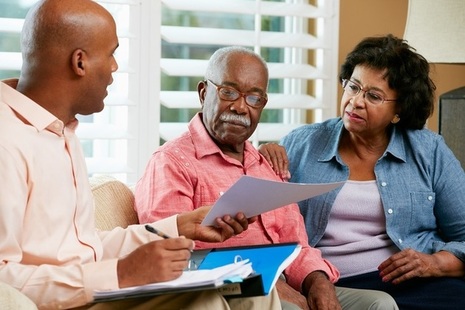 Image of eldery couple looking at paperwork with their financial adviser or younger male family member