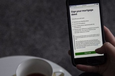 mobile phone screen showing sign your mortgage deed, with a cup of tea