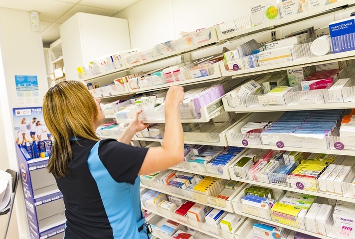 Pharmacist reaching for medicines in hospital pharmacy