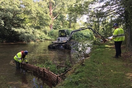 Stabilising and re-profiling river bank with an amphibious excavator.