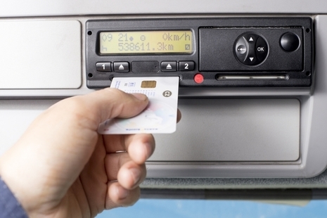 Driver inserting a digital tachograph card into a tachograph unit