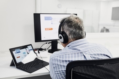 Man hosting webinar, wearing headphones infront of laptop.