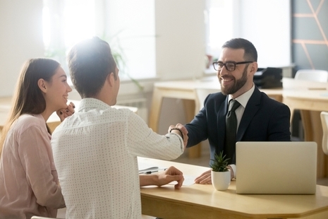 Smiling lawyer shaking hands with young couple