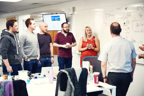 Members of a team having a discussion around a whiteboard