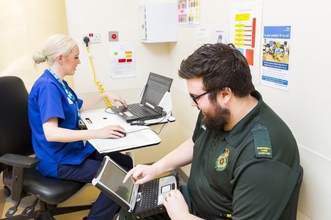 Doctor and paramedic working on laptops