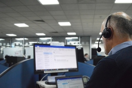 Man with telephone headset looking at computer screen