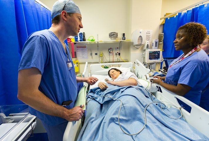 Surgeon and medical staff talking to patient in bed
