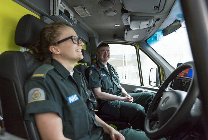 Two paramedics chatting in the front of an ambulance