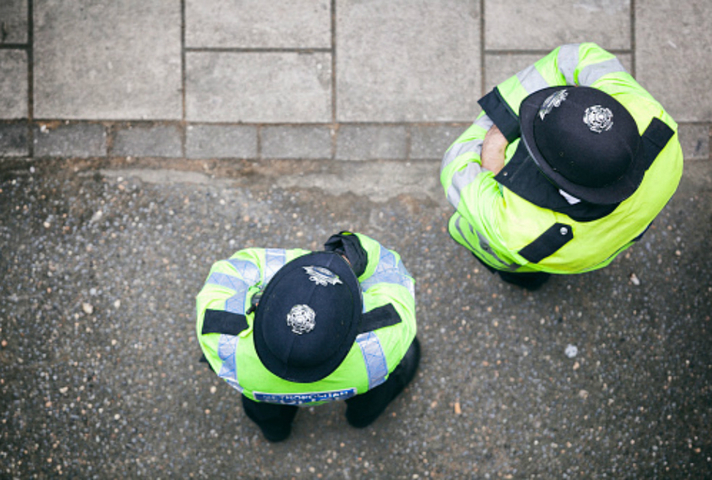 2 police officers standing in the street, photographed from above