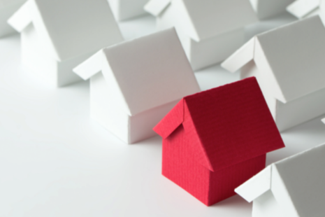 Red paper house among white paper houses.