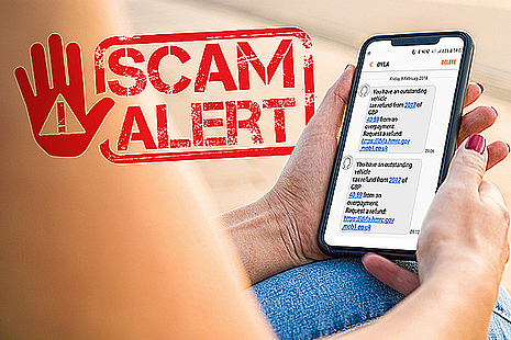 Hands holding a mobile phone with a scam text message