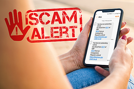 Hands holding a mobile phone with a scam text message on it