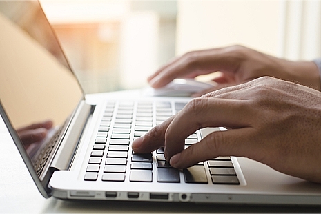 Hands typing on a laptop keyboard.