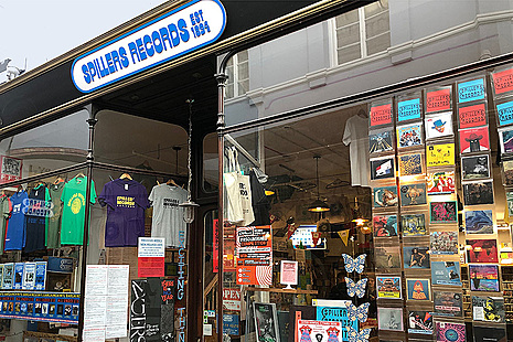Y tu allan i ffenestr siop, gydag arwydd yn arddangos Spillers Records Est 1894.