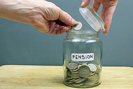 Hand putting coins in jar marked pensions