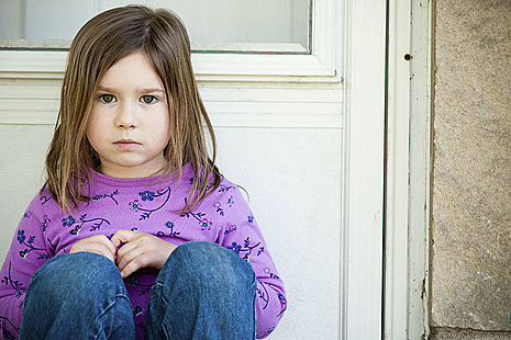 Young girl sitting outside front door.