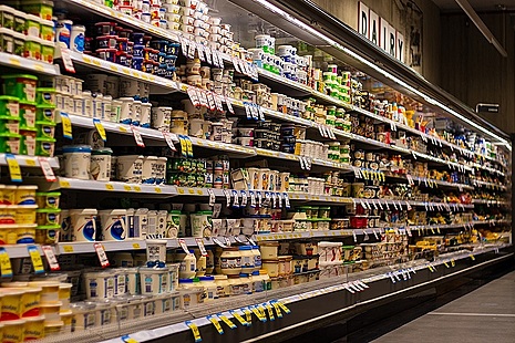 Fully stocked refrigerated shelves in dairy section of shop