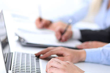 Stock image of a hand typing on a laptop.