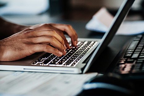 Hands typing on a laptop