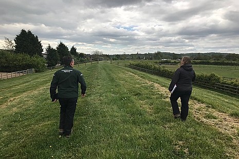 Two Environment Agency staff in a field socially distancing.