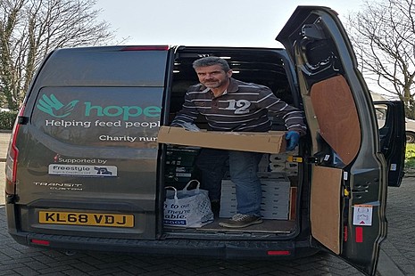 Volunteer carrying crates out of the Hope Enterprises van