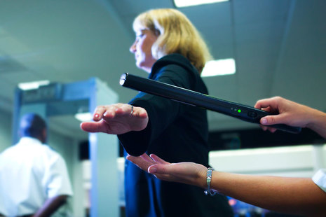 Woman being scanned with a security wand entering a building