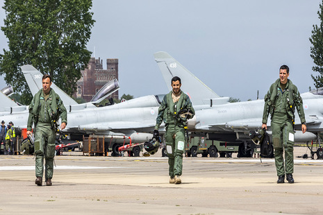 Image depicts three uniformed men walking in front of two Typhoon aircraft