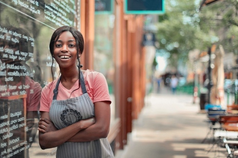 Smiling waitress leaning against restaurant window.