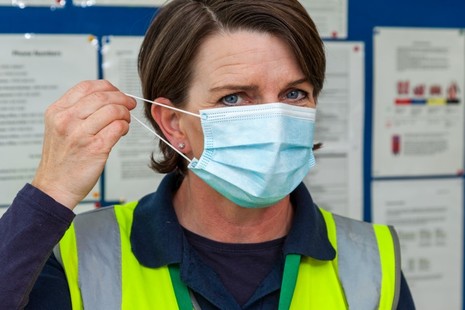 Photo of a driving examiner putting on a face covering.