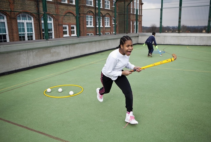 A girl playing hockey in a school playground