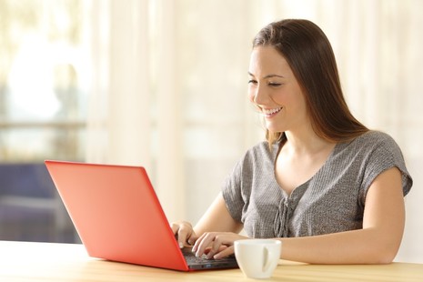 Stock image of a girl typing at a red laptop.