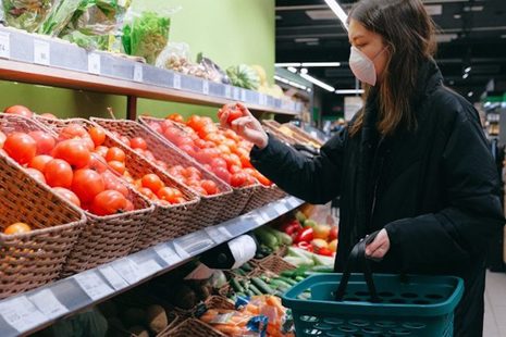Woman wearing a face mask, shopping for tomatoes in a supermarket