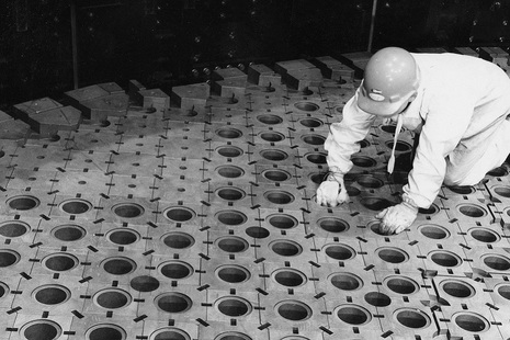 A man kneeling by some graphite blocks