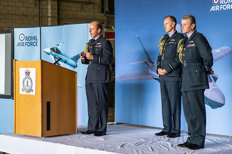 Image depicts Air Chief Marshal Mike Wigston with two deputies in uniform on a stage.