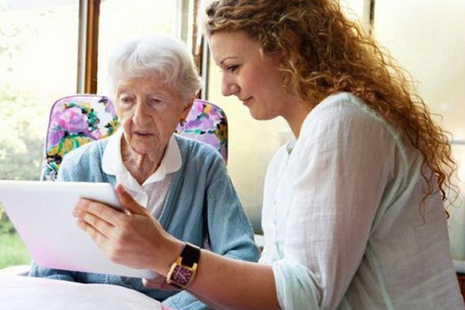 Woman showing older lady a tablet