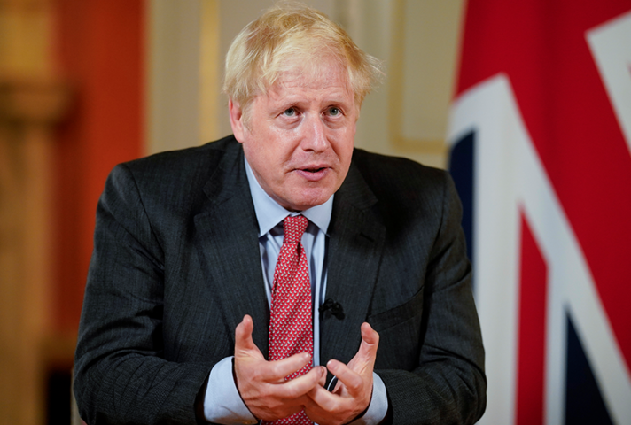 Photo of Boris Johnson sat at a desk.