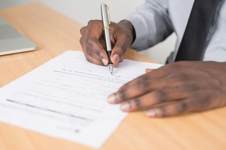 A close up of a person's hand filling in forms.
