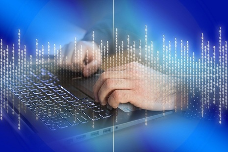Hands typing on keyboard with overlay of binary code symbols