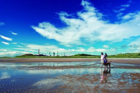 Family walking on a beach with Sellafield - in Copeland - in the background