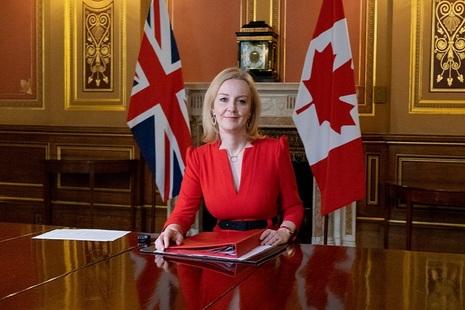 International Trade Secretary Liz Truss in front of flags of UK and Canada