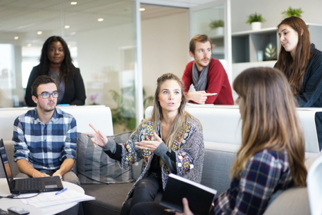 A group of people sitting on sofas having a discussion.