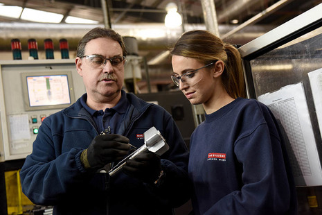A man and a woman look at a shell they are working on.