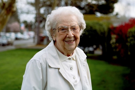An elderly woman outdoors, smiling.
