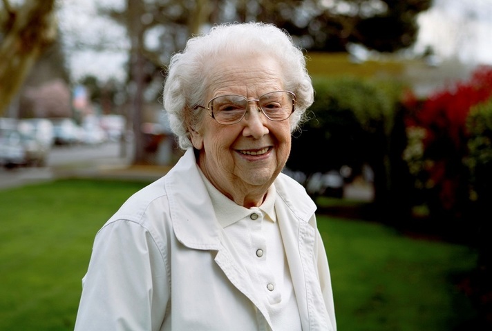 An elderly woman outdoors, smiling.